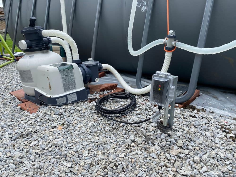 Pool filter system with pump, hoses, and electrical control near a gray water tank.