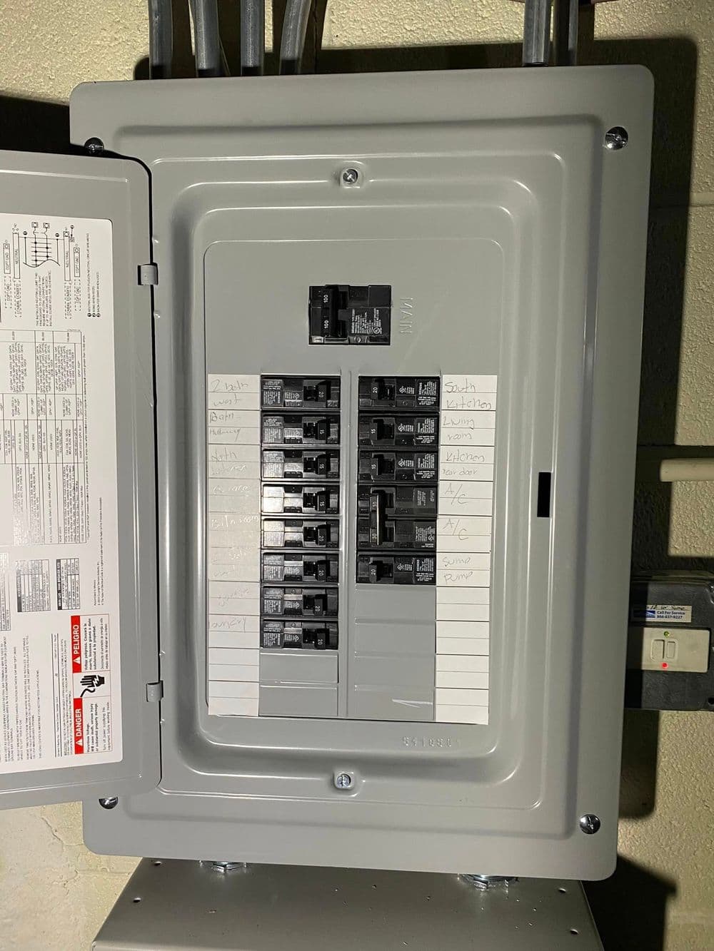 Electrical panel with labeled circuit breakers and wiring details for home safety.