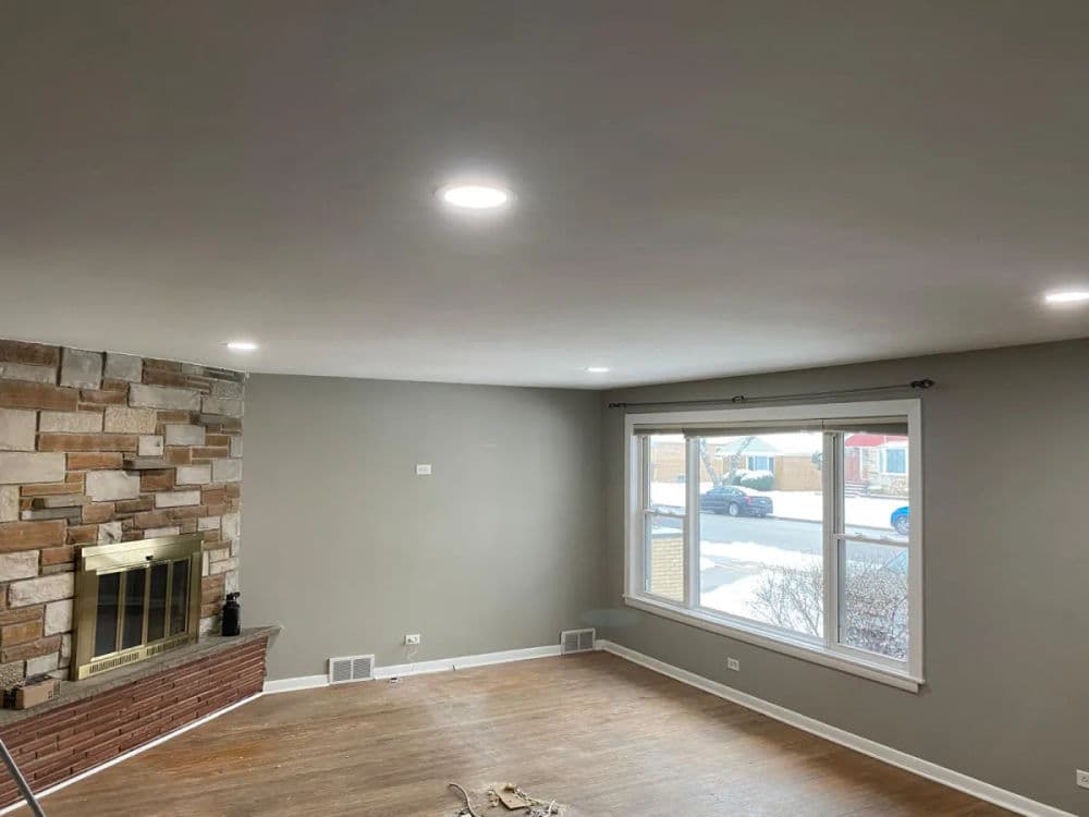 Spacious living room with recessed lighting, stone fireplace, and large window.