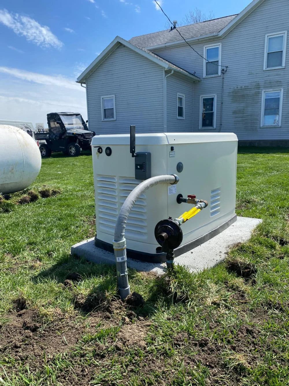 Home generator installed on concrete pad in grassy yard with a house in the background.