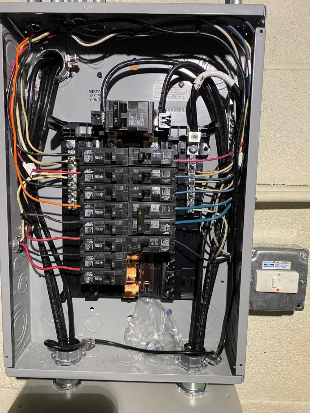 Electrical panel with circuit breakers and wires, showcasing wiring organization and safety features.